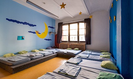 Ein Schlafraum in beruhigenden Blautönen mit Mond und Sternen an der Wand